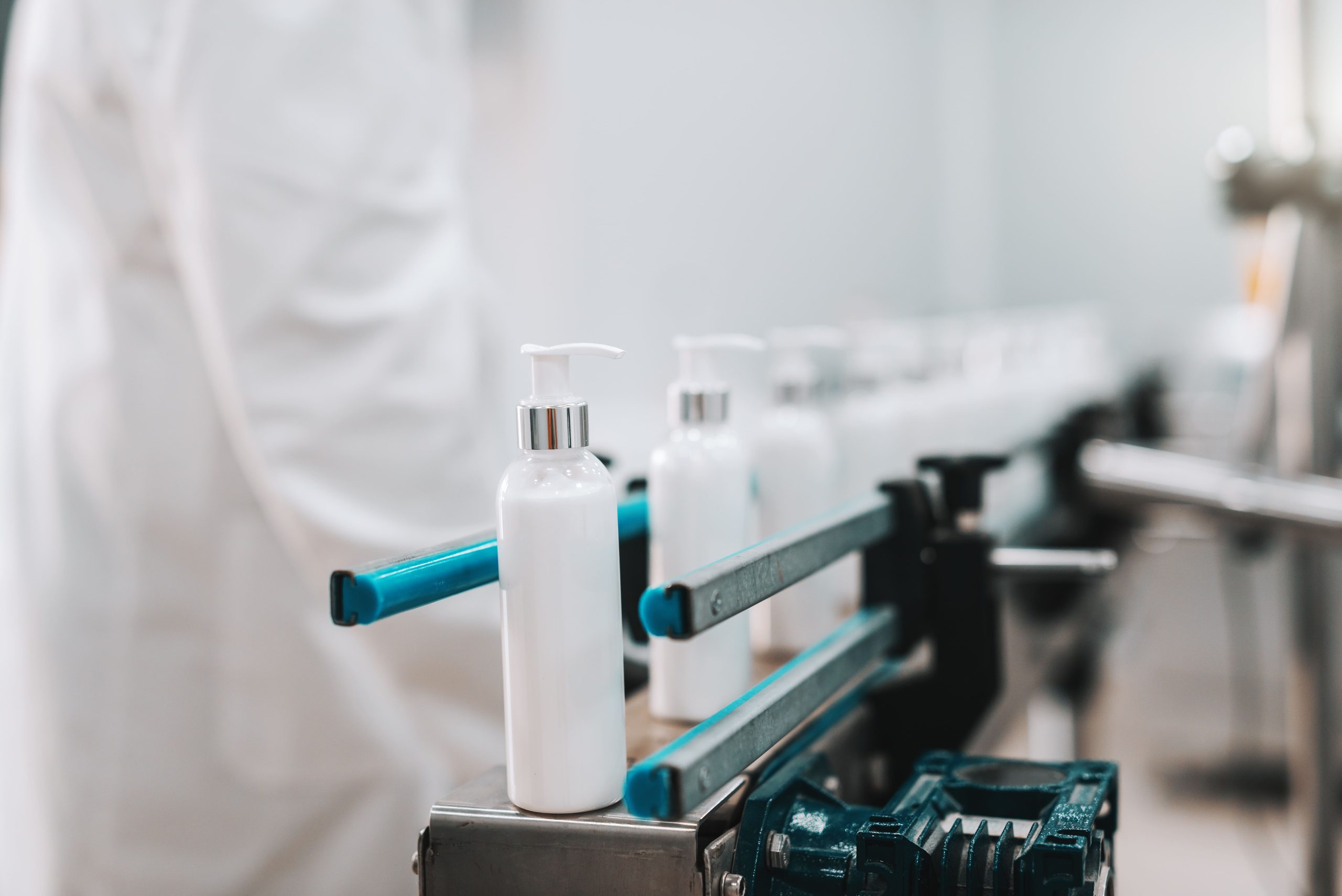 close-up-bottles-with-hair-conditioner-row-exit-pouring-machine-1-scaled