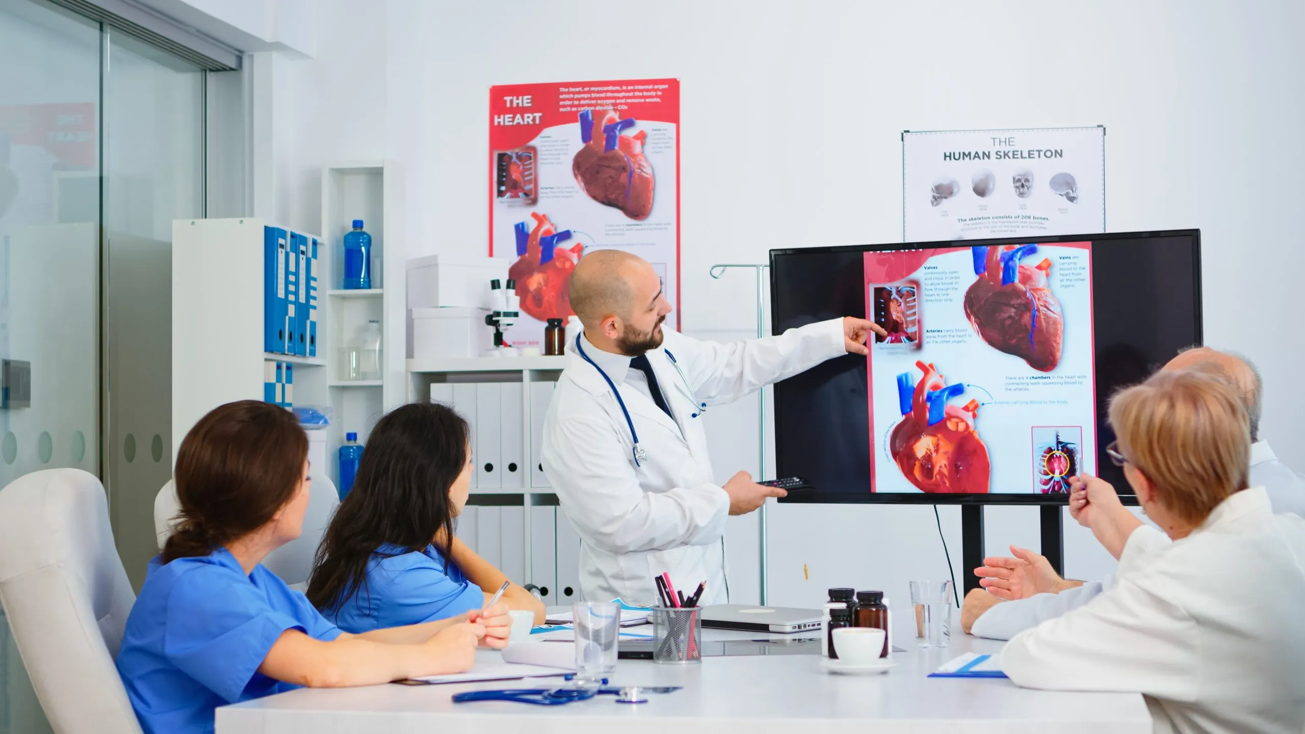USA Coronary Artery Imaging Equipment Market Outlook to 2030 experienced-man-doctor-analysing-heart-issues-image-together-with-cvalified-colleagues-meeting-room-pointing-monitor-doctors-discussing-diagnosis-about-treatment-patients-1-scaled