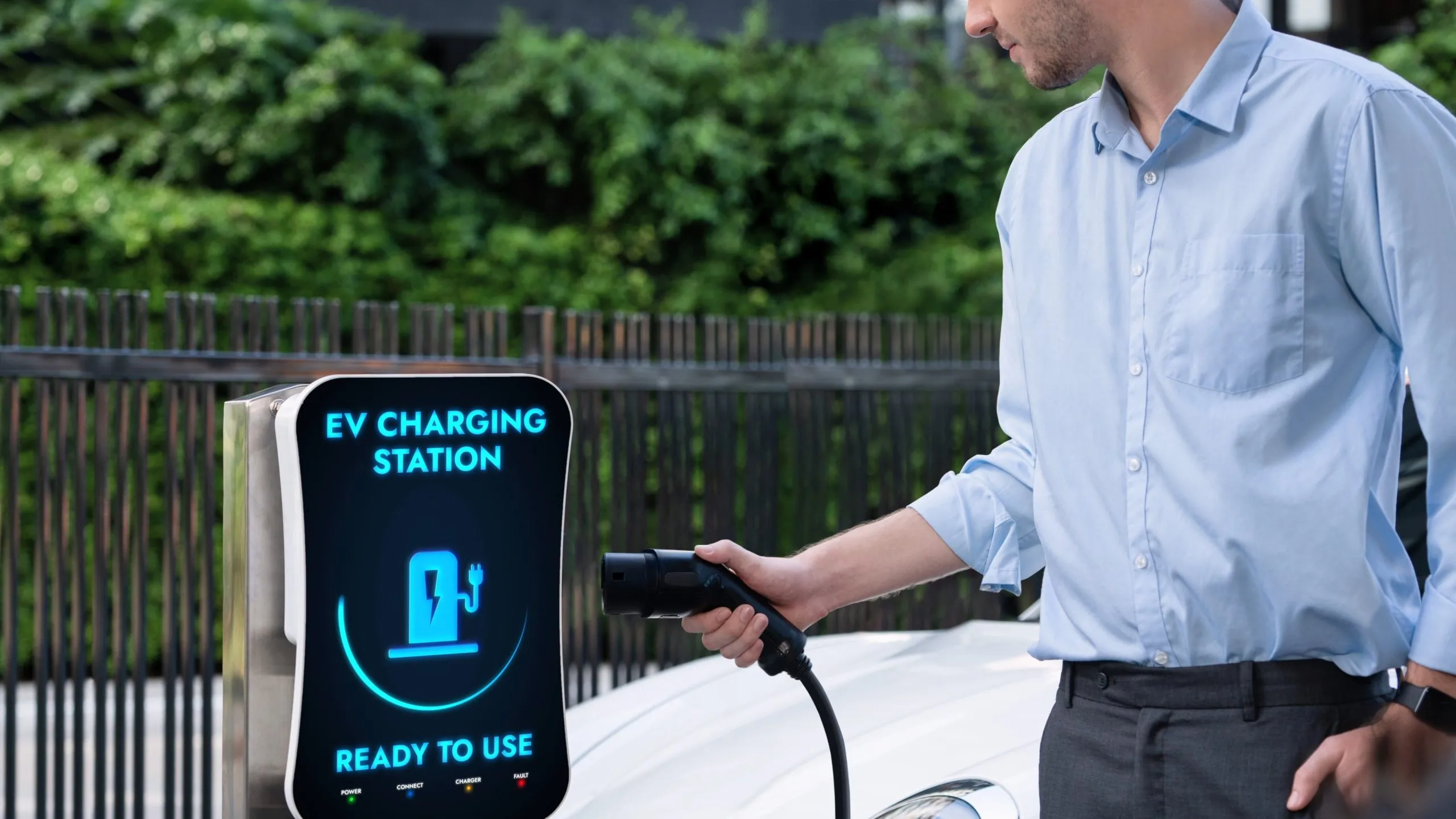 USA Wireless EV Charging Systems Market Outlook 2030 businessman-pull-hold-ev-charger-plug-form-charging-station-peruse-1-scaled