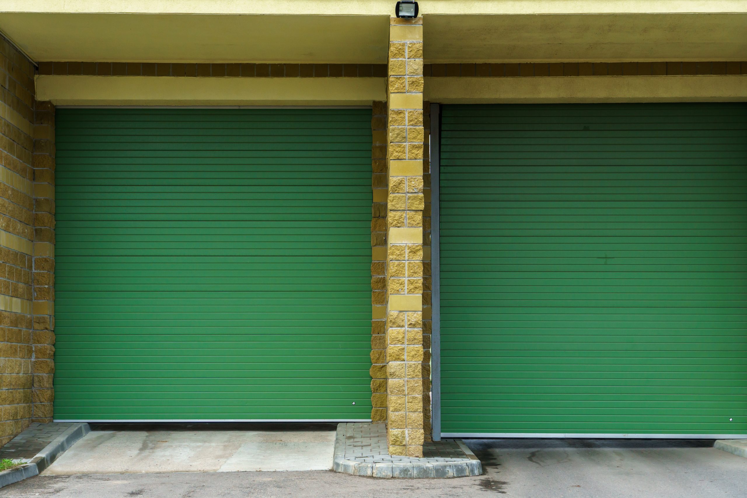 large-modern-garage-made-beige-brick-green-roller-gates-video-surveillance-system-entrance-garage-safe-conditions-storing-cars-property-scaled