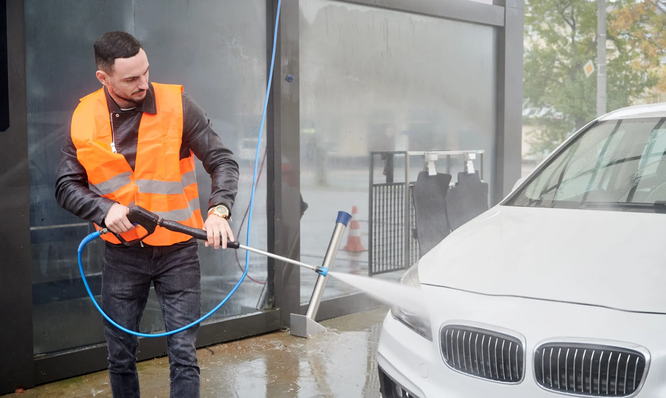 USA Car Wash Services Market Outlook 2030 man-washing-car-carwash-station-wearing-orange-vest-1-scaled