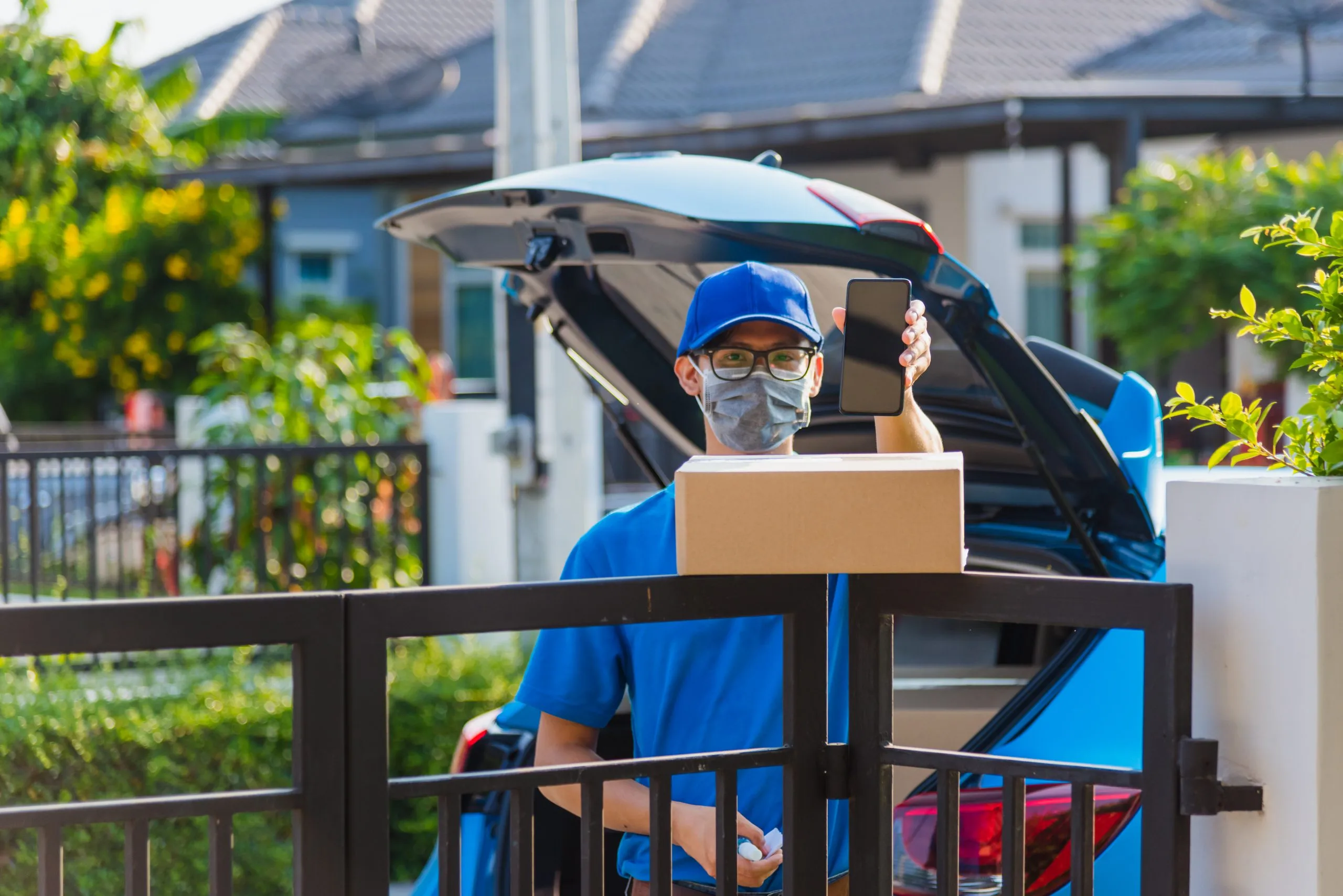 USA Last-Mile Delivery Market Outlook to 2035 asian-delivery-man-courier-place-deliveries-boxes-home-showing-mobile-phone-blank-screen-customer-sign-he-protective-face-mask-service-curfew-quarantine-pandemic-coronavirus-covid-19-1-scaled