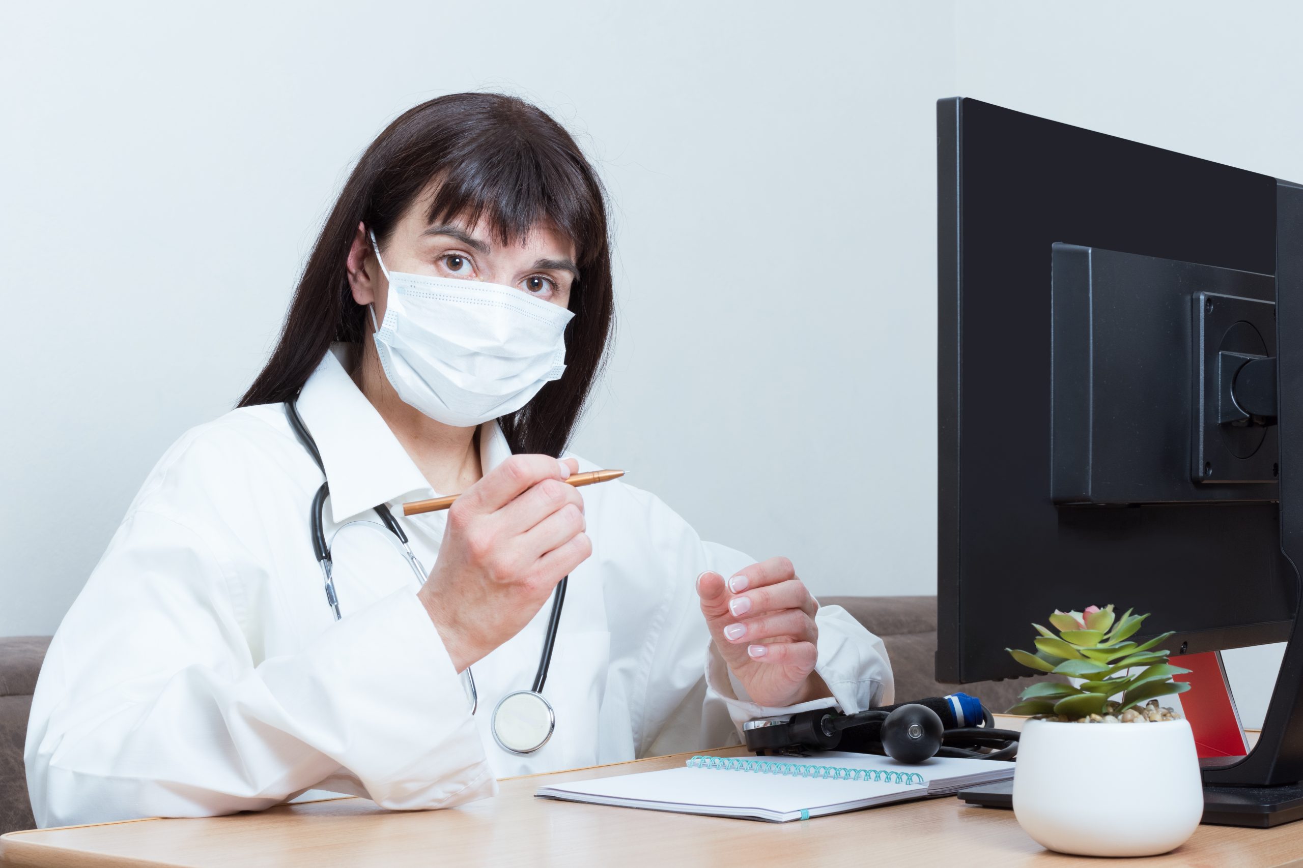 female-doctor-wearing-medical-protective-mask-is-looking-you-while-sitting-table-office-scaled