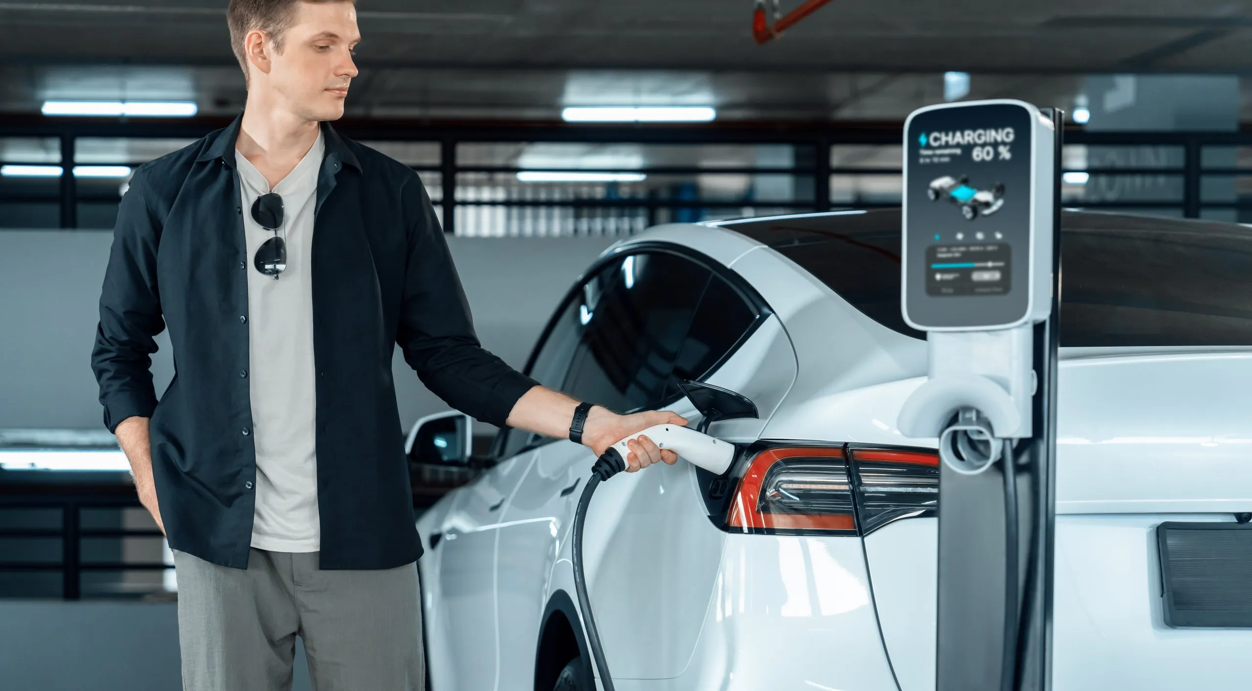 UK EV Battery Market Outlook to 2035 young-man-travel-with-ev-electric-car-shopping-center-parking-lot-innards-scaled