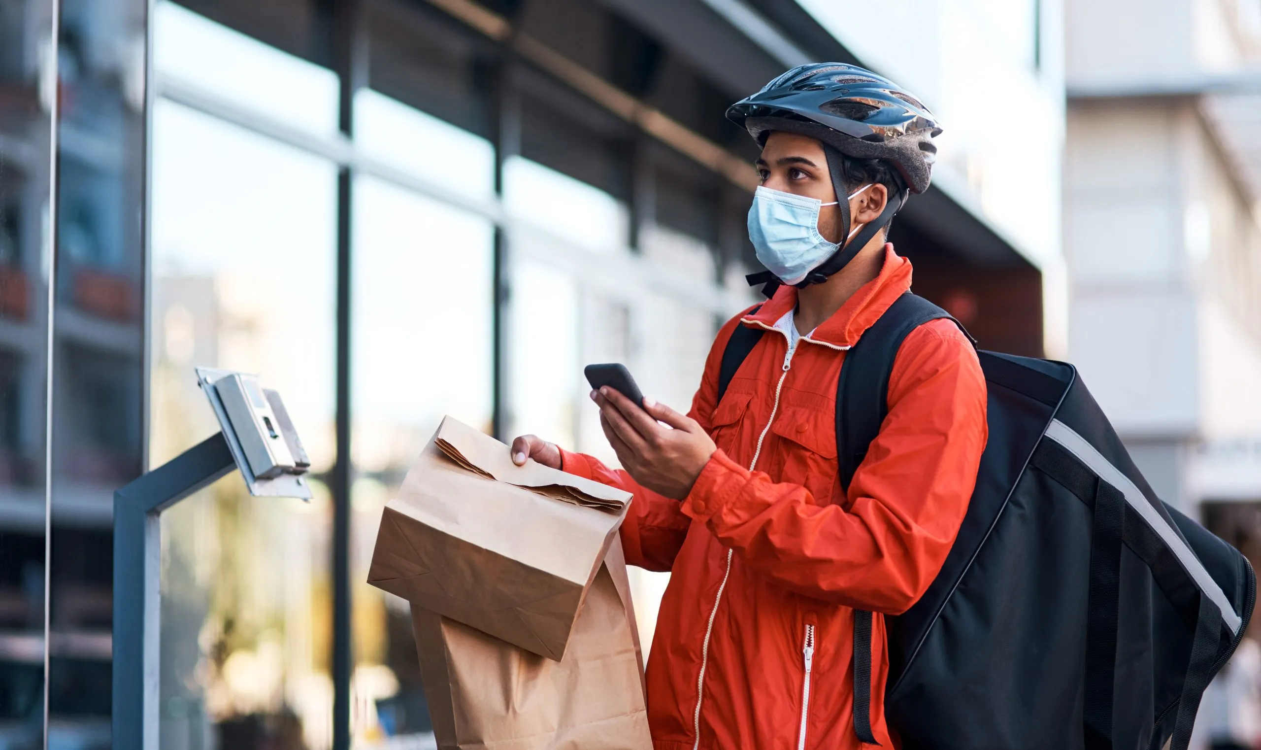 Nigeria’s Last-Mile Delivery Market Projected to Reach $5 Billion with E-Commerce Growth and Tech Innovations app-brought-me-this-address-shot-masked-man-using-his-cellphone-while-doing-food-delivery-scaled