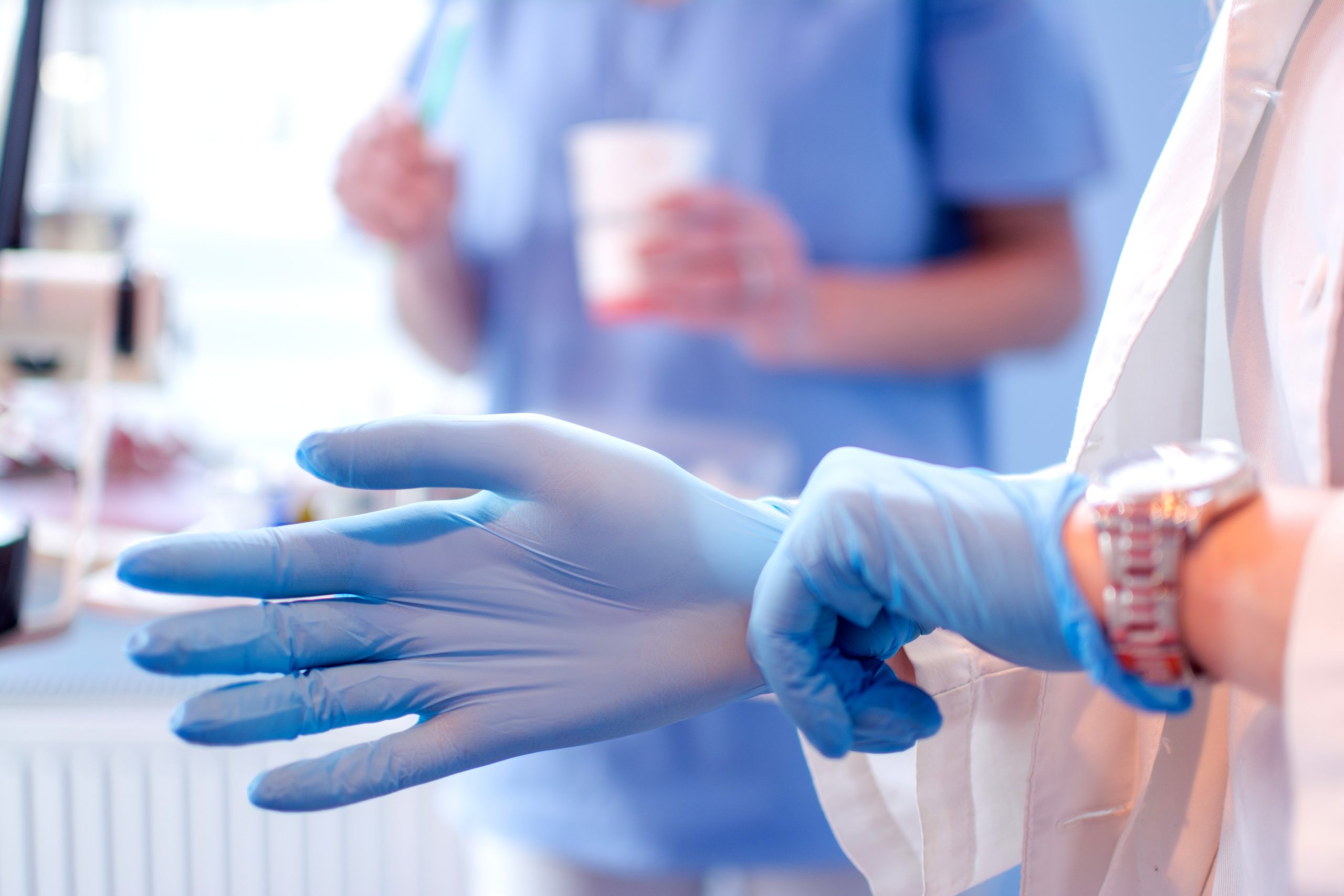close-up-female-doctors-hands-putting-blue-sterilized-surgical-gloves-medical-clinic-scaled