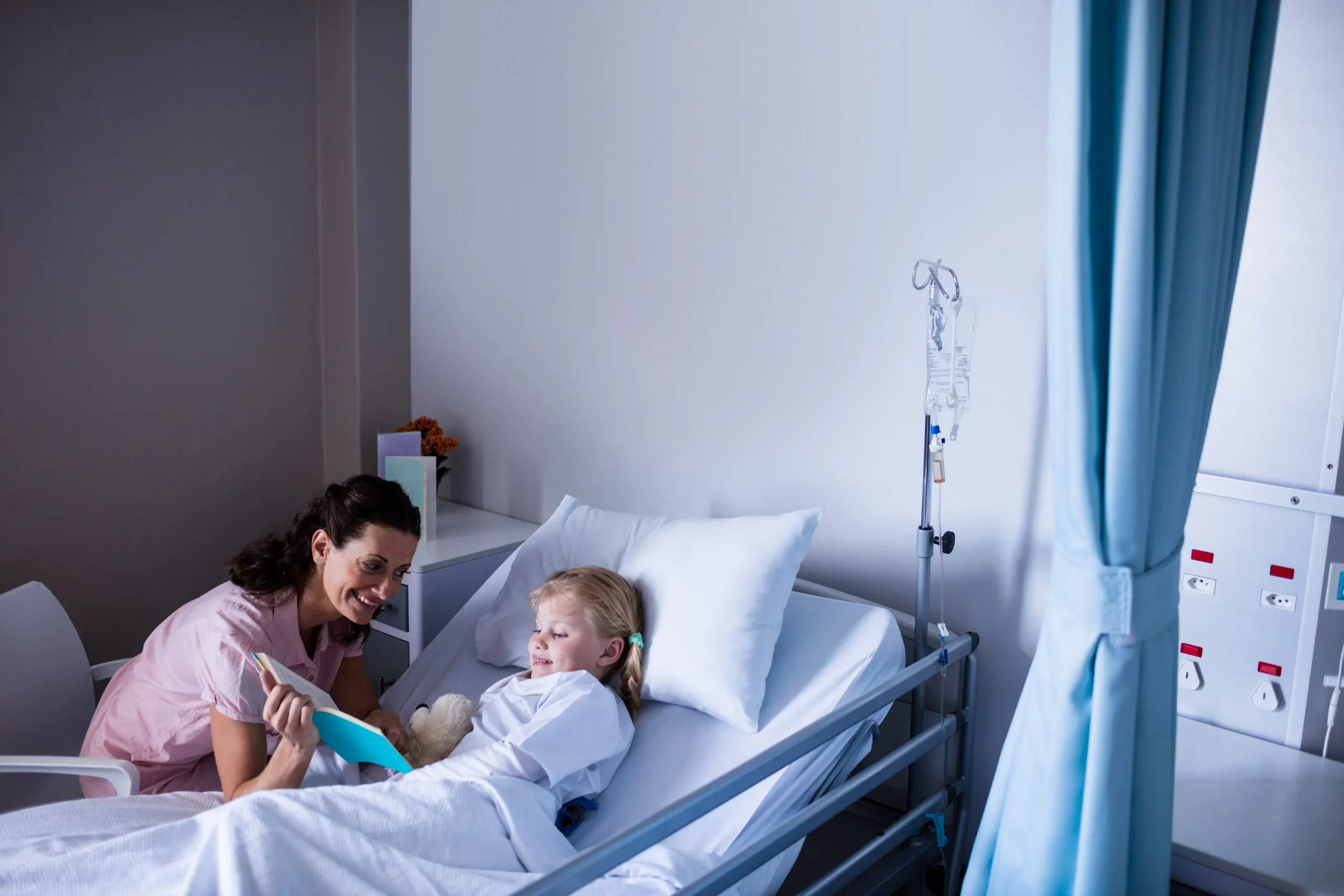 KSA Pediatric Beds Market Outlook 2035 girl-hospital-bed-reading-book-with-her-mother-scaled