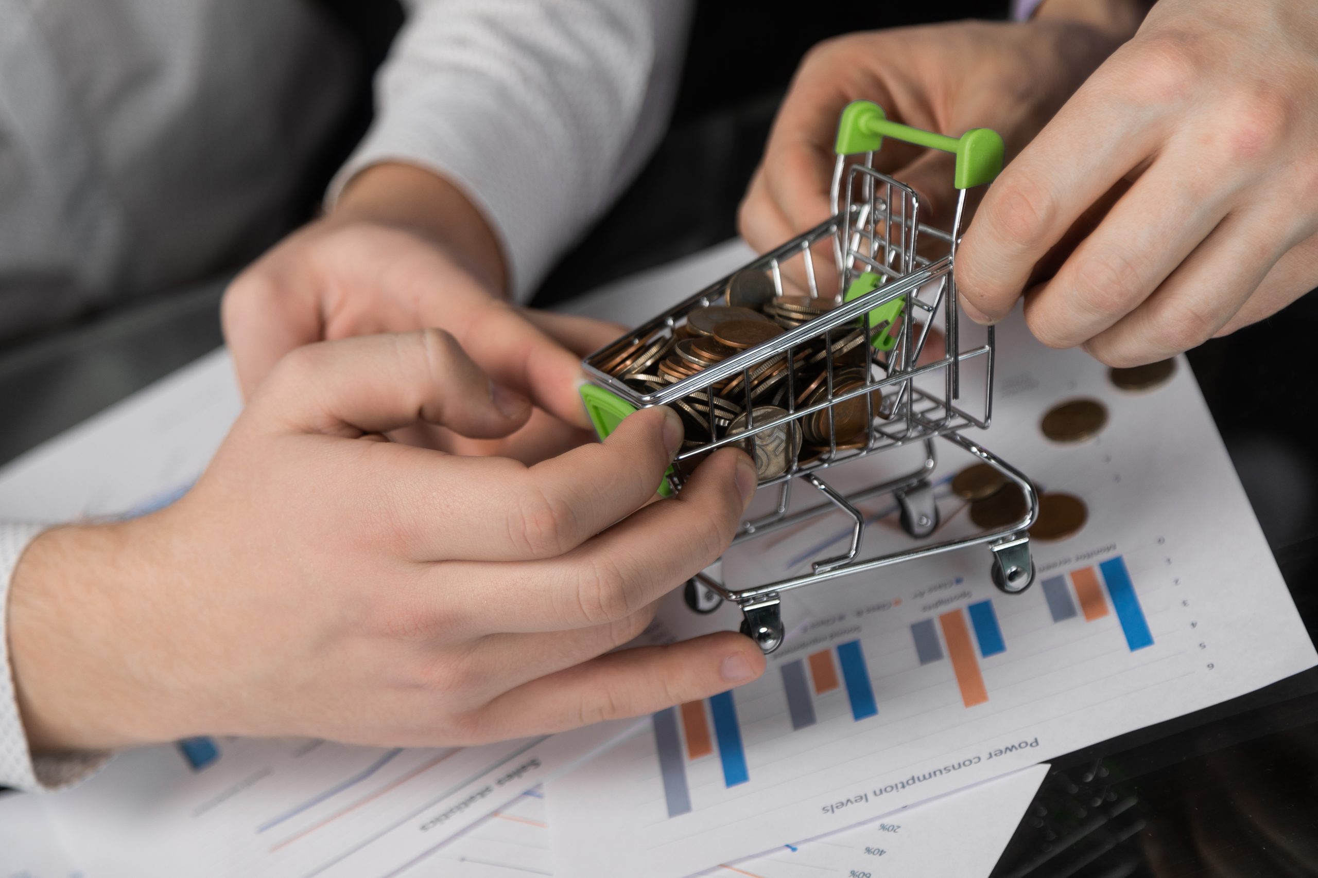 men-s-hands-pulled-different-directions-dummy-shopping-cart-filled-with-coins-scaled