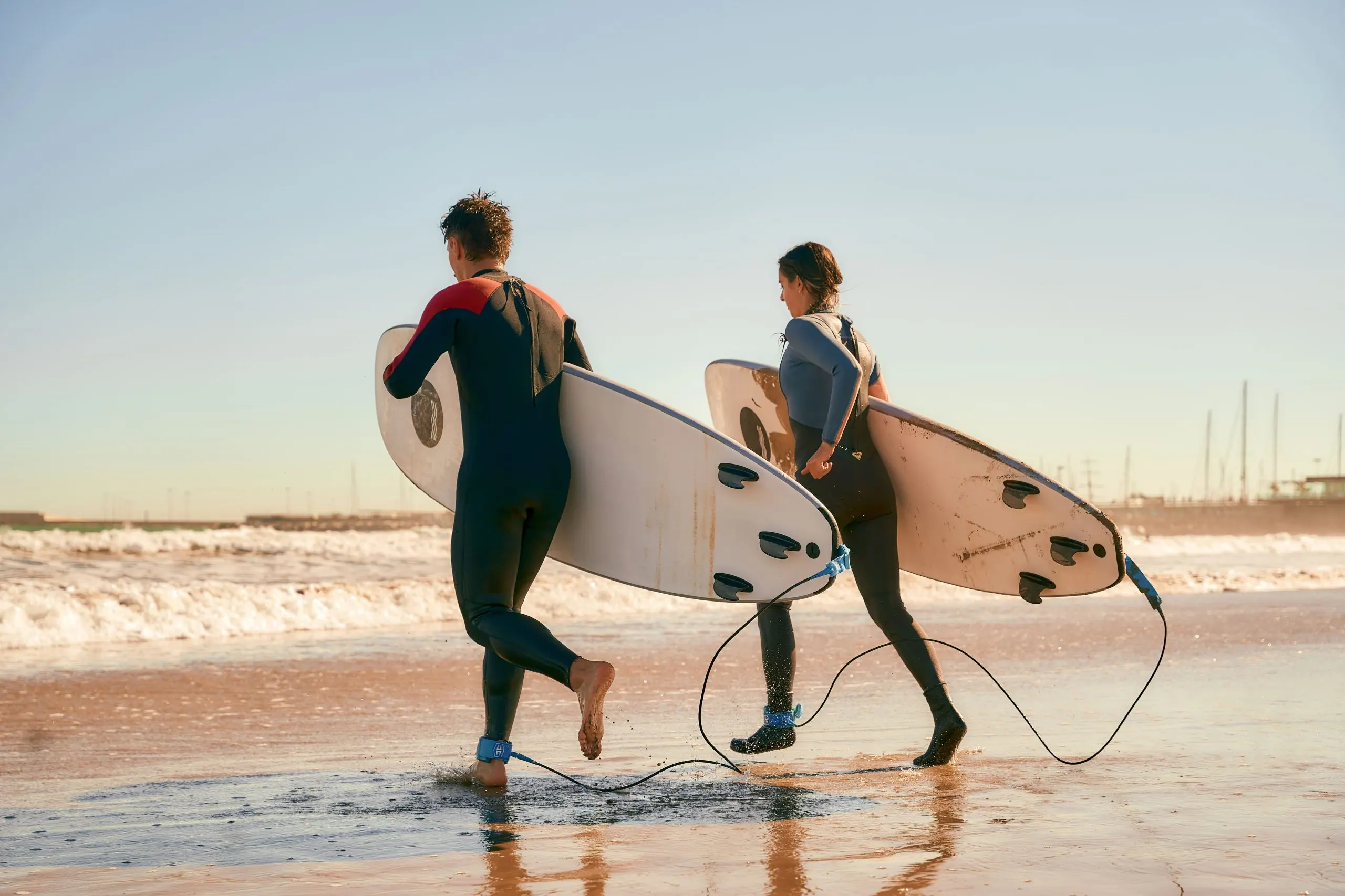 Brazil Surfing Equipment Market Outlook to 2035 couple-surfers-with-surfboards-wetsuit-entering-towards-ocean-surfing-waves-1-scaled