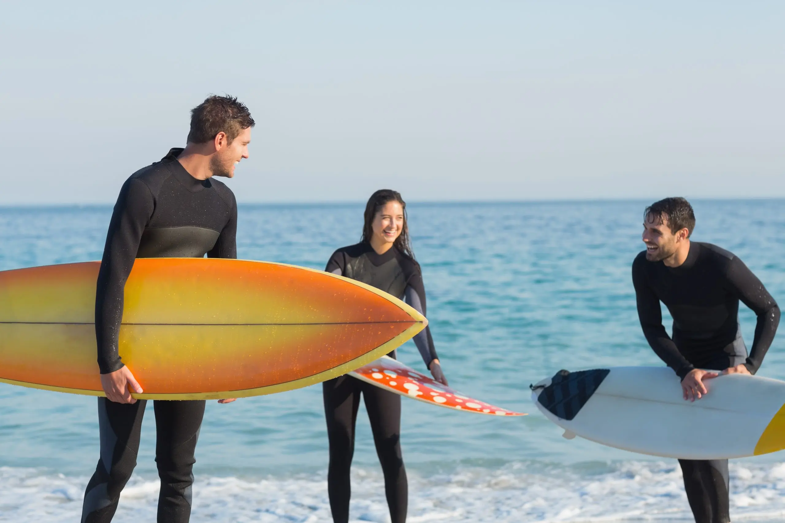 USA Surfing Equipment Market Outlook to 2035 group-friends-wetsuits-with-surfboard-sunny-day-scaled