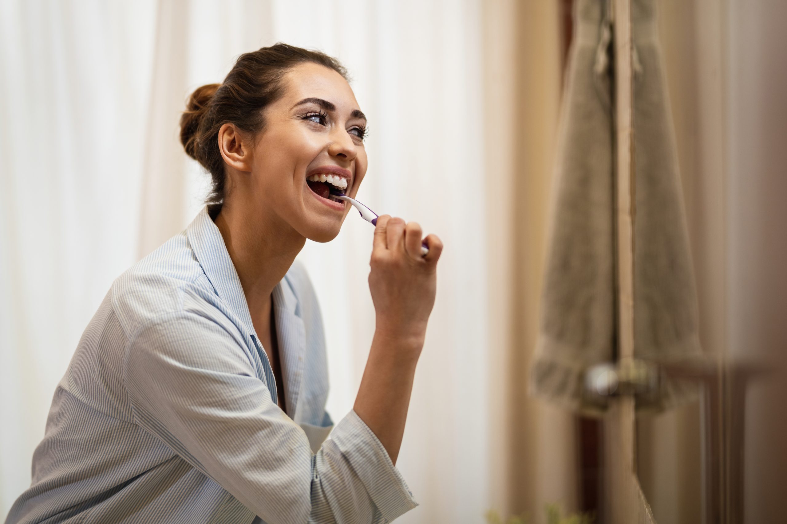 happy-woman-cleaning-her-teeth-with-toothbrush-morning-scaled