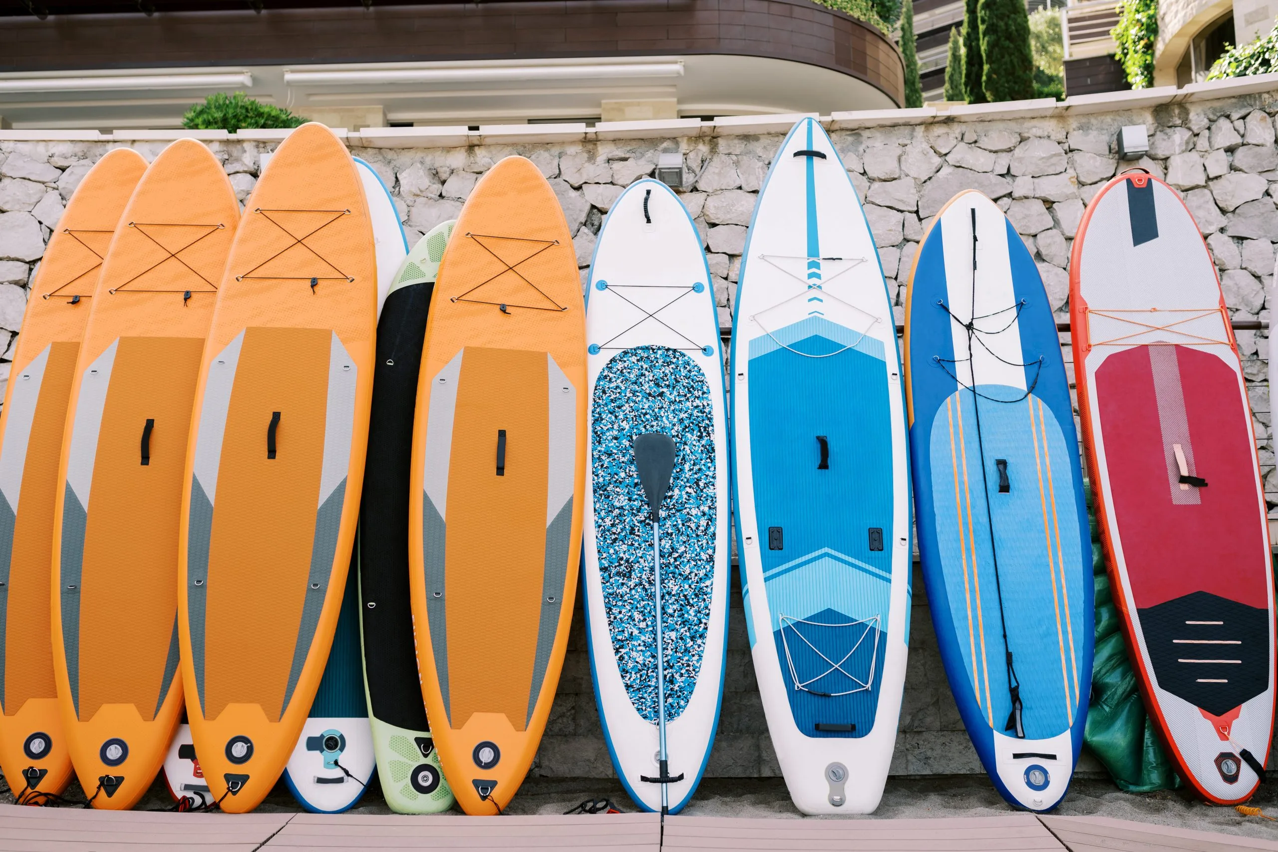 UAE Surfing Equipment Market Outlook to 2035 row-colorful-surfboards-stands-near-stone-fence-beach-1-scaled