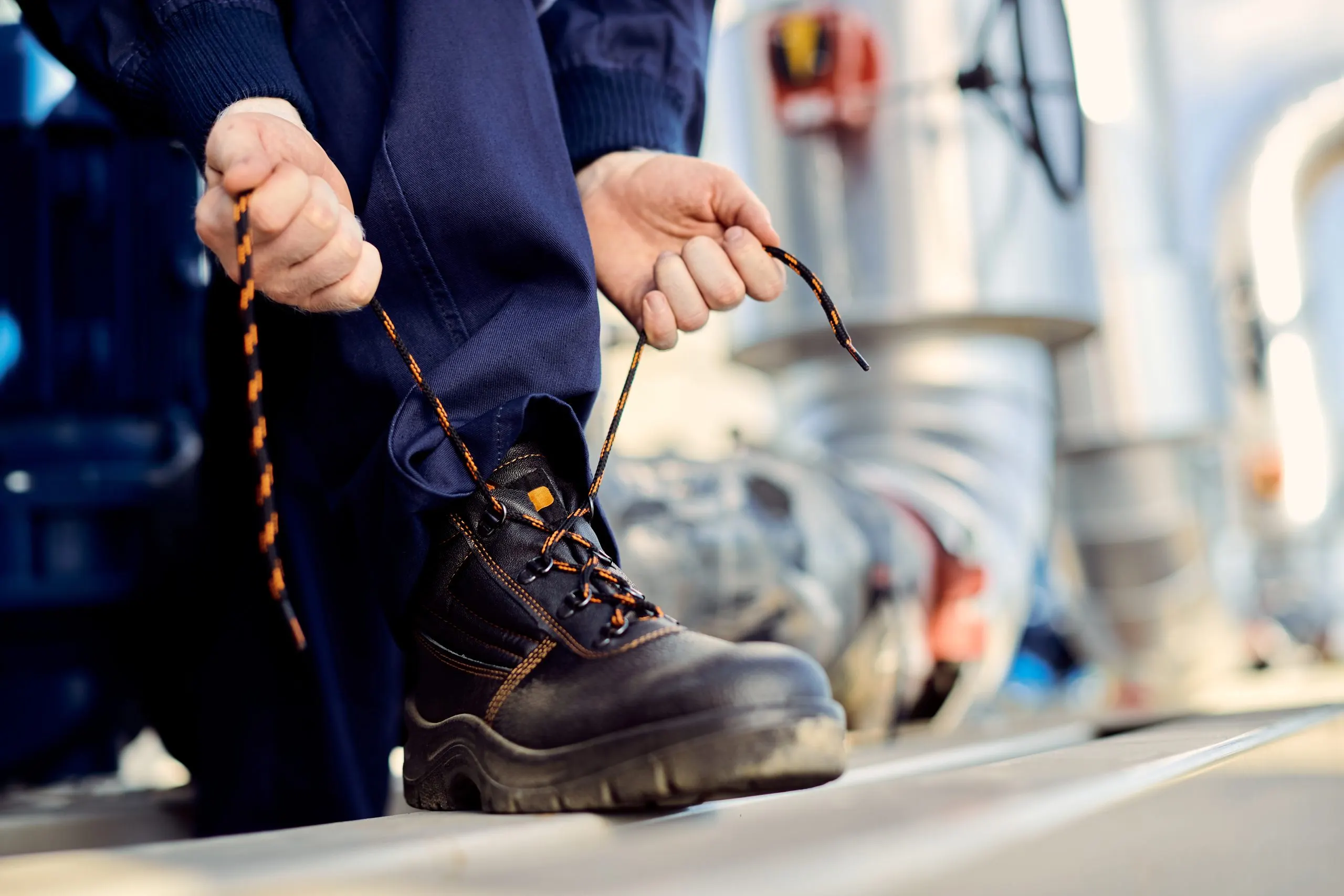 India Industrial Protective Footwear Market Outlook to 2035 unrecognizable-manual-worker-typing-shoelace-construction-site-scaled