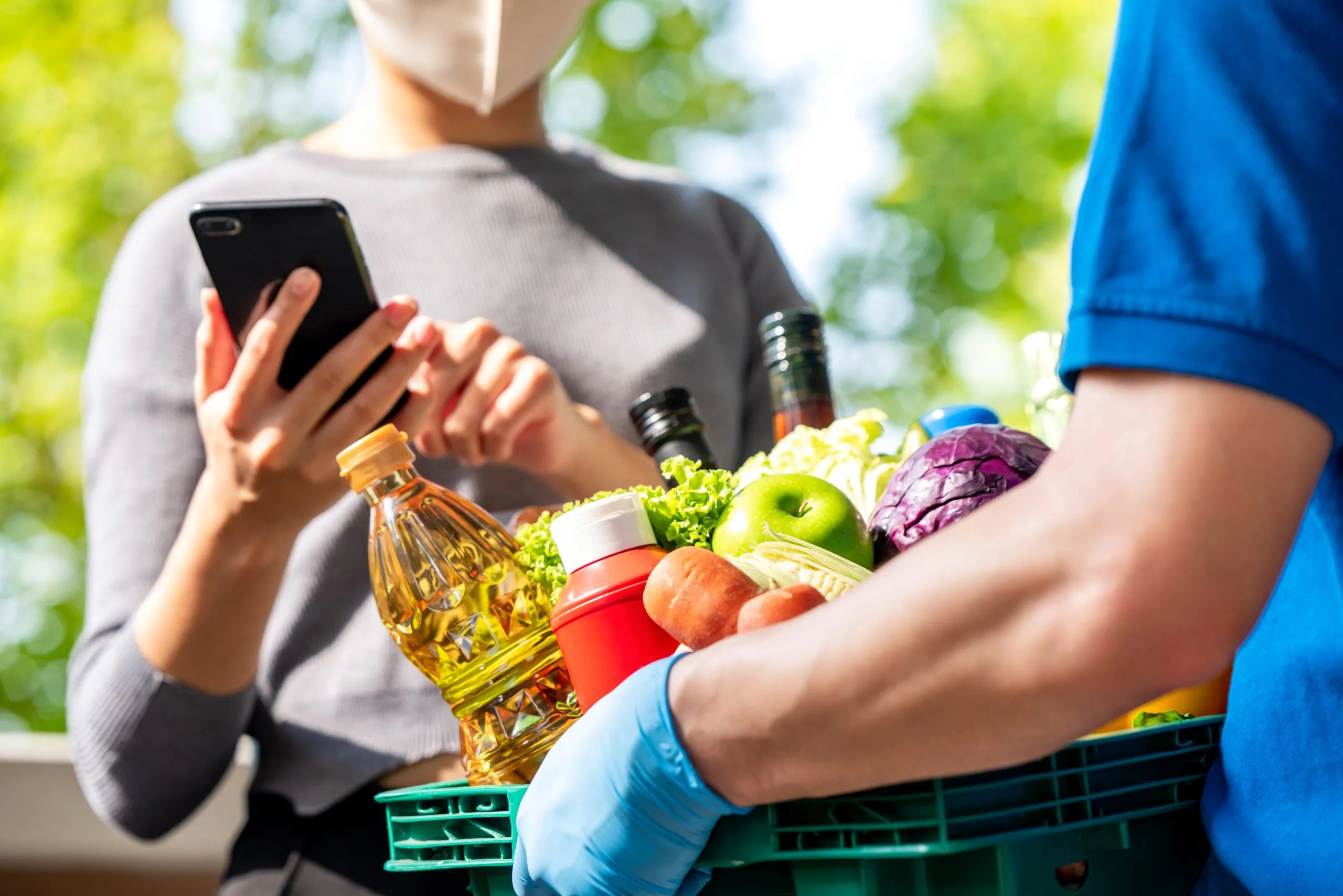 UK Online Grocery Delivery Market Outlook to 2035 woman-customer-wearing-face-mask-checking-grocery-that-ordered-online-delivered-by-deliveryman-home-food-delivery-service-times-covid-19-concept-scaled