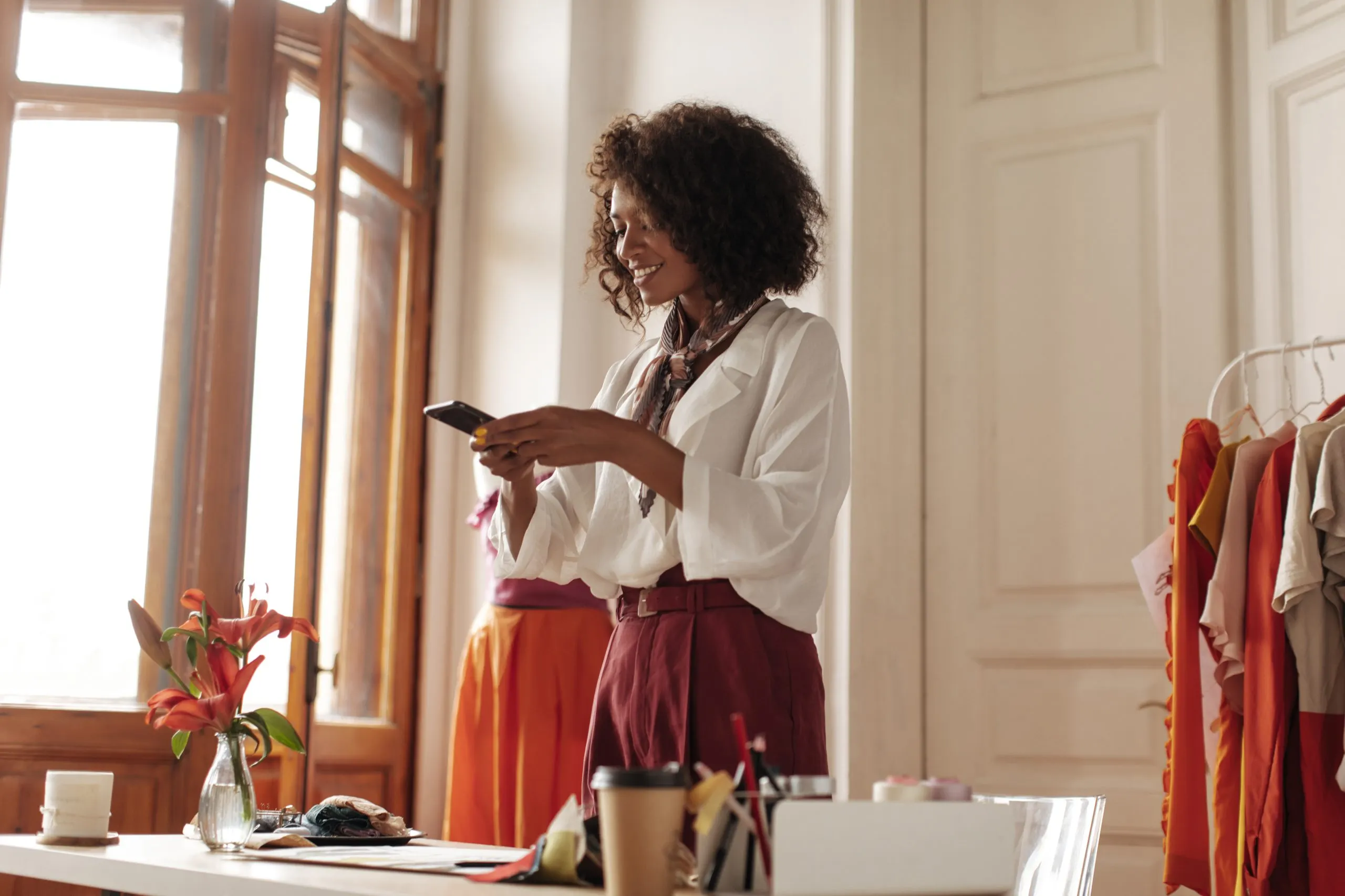 Nigeria Fashion Rental Market Benefits from 10 to 15 Percent E-Commerce Growth fashionable-curly-darkskinned-woman-burgundy-pants-white-blouse-takes-photo-textile-samples-holds-phone-smiles-office-scaled