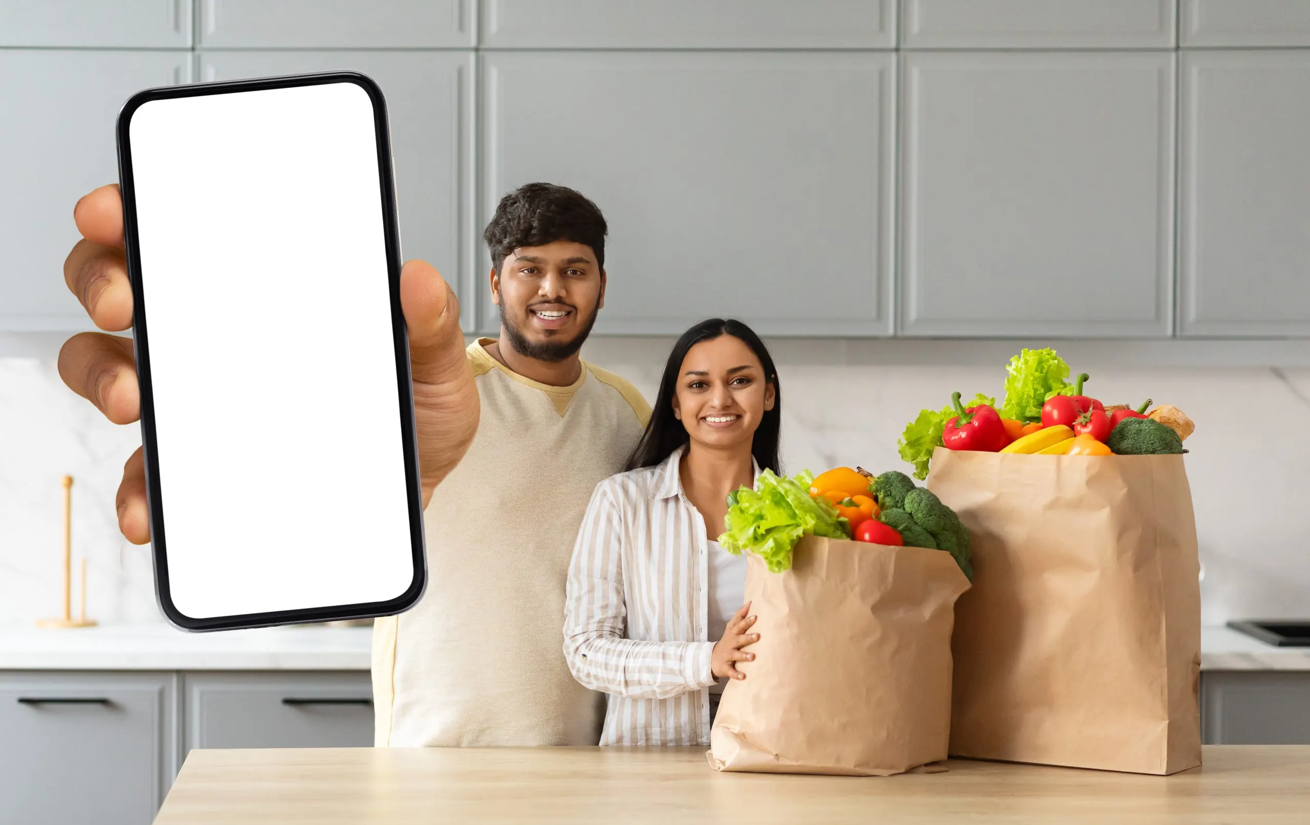 UAE Online Grocery Delivery Market Surpasses $4 Billion Driven by 20 Percent Annual Growth happy-young-indian-spouses-order-grocery-online-showing-smartphone-scaled