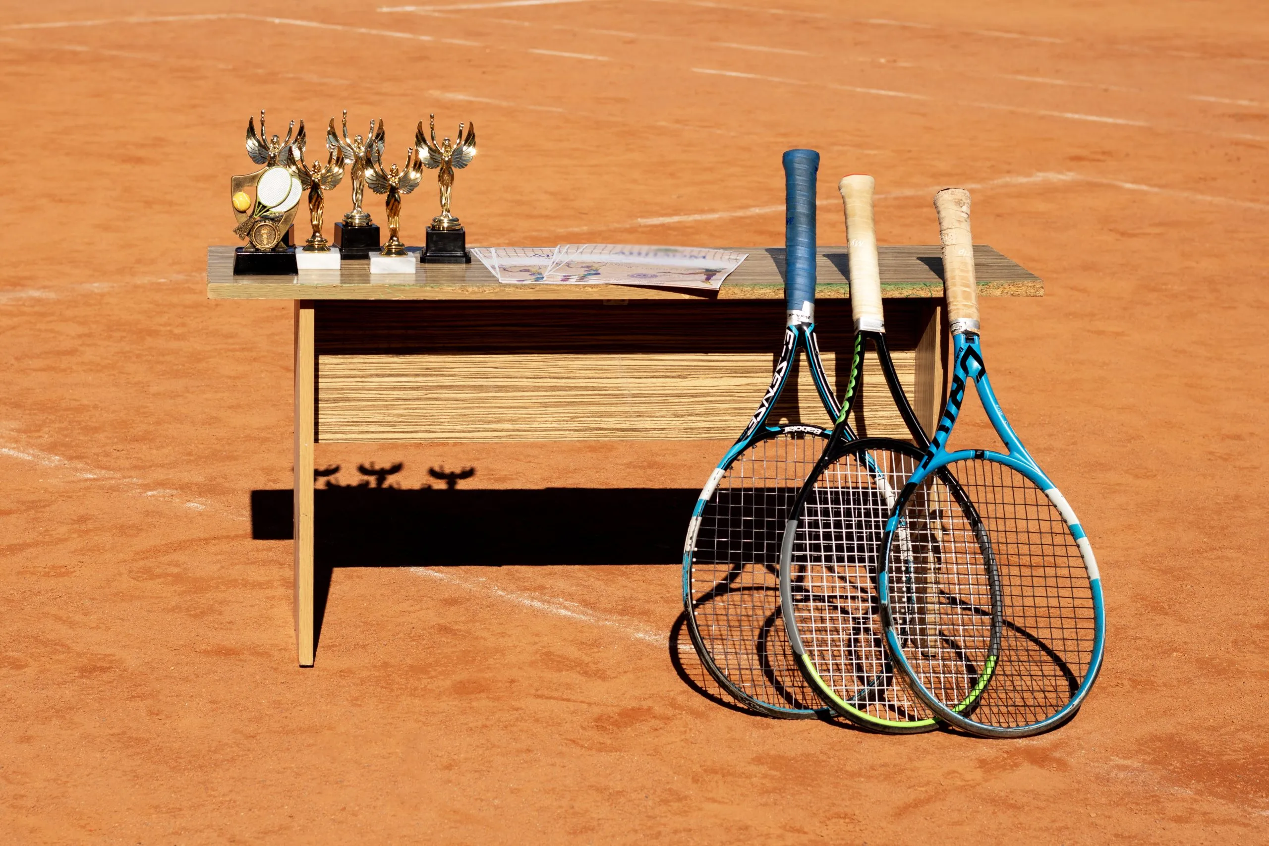 Nigeria Tennis Equipment Market Expands with 4.28 Percent CAGR Driven by Rising Participation tennis-trophies-wooden-table-with-rackets-clay-court-backdrop-sports-event-image-scaled