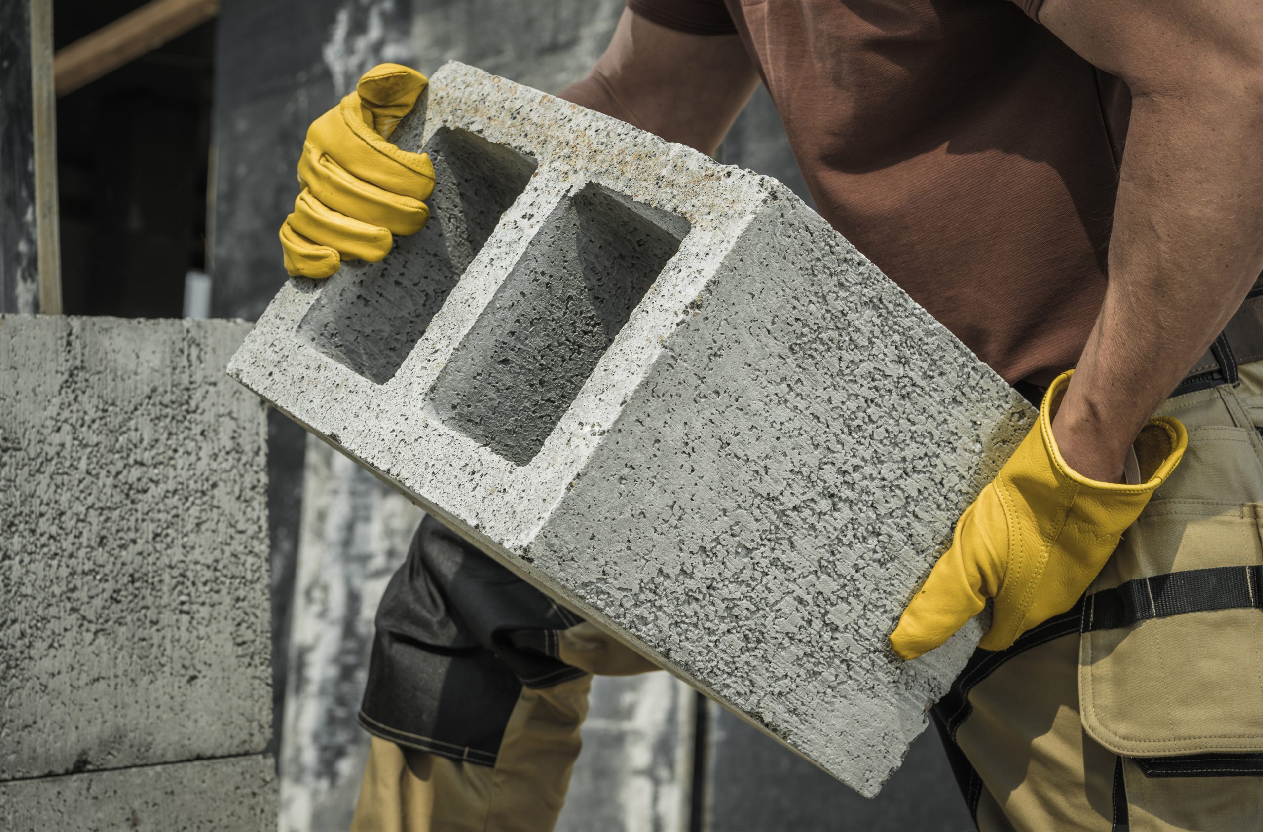 construction-worker-moving-hollow-dense-concrete-blocks-scaled