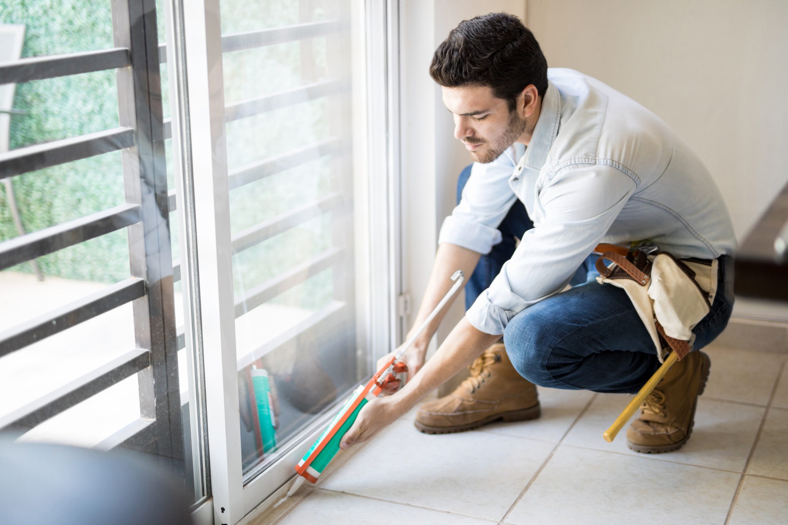 Germany Construction Sealants Market Outlook to 2035 young-handyman-wearing-tool-belt-using-sealing-gun-seal-glass-door-frame-house-scaled